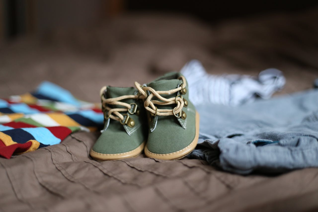 Adorable green baby booties surrounded by colorful clothes, perfect for infant fashion.